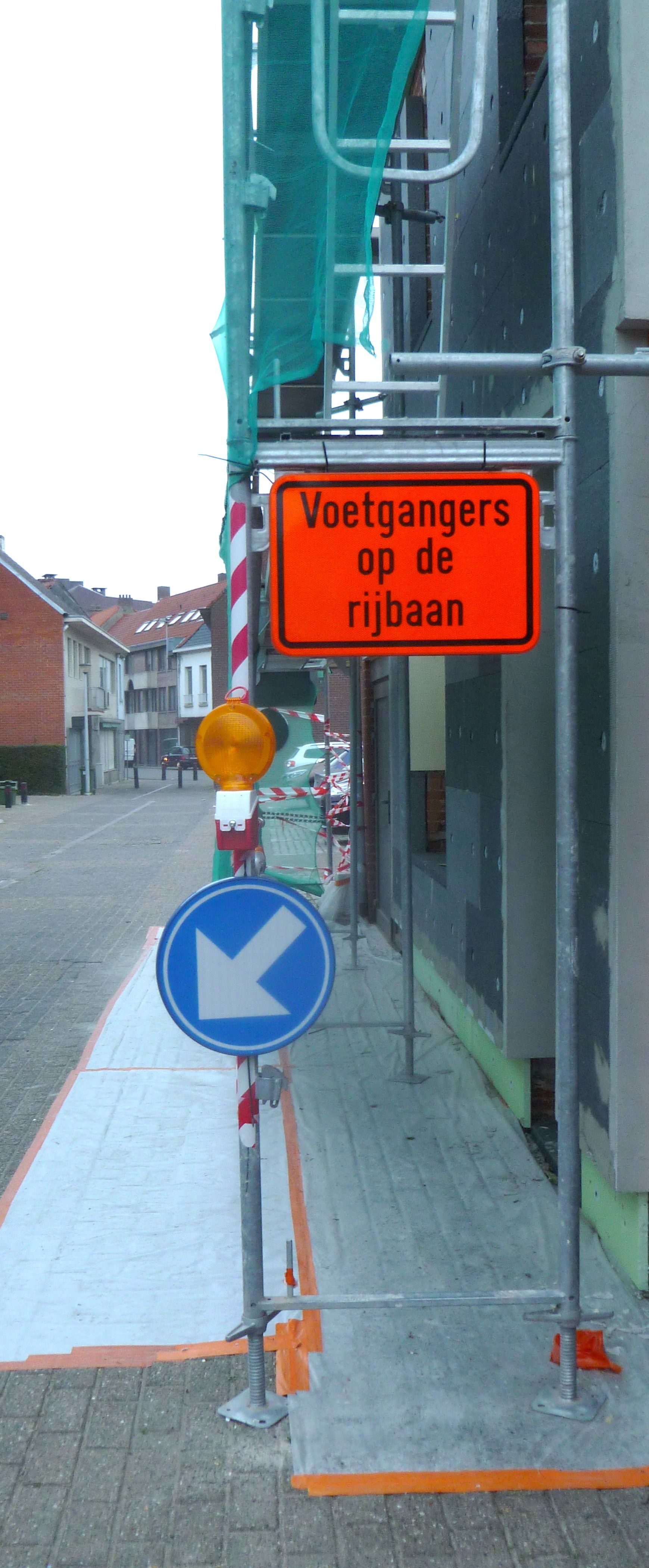 Een stelling op het voetbad met een oranje bord dat aangeeft dat voetgangers op de openbare weg moeten stappen. 