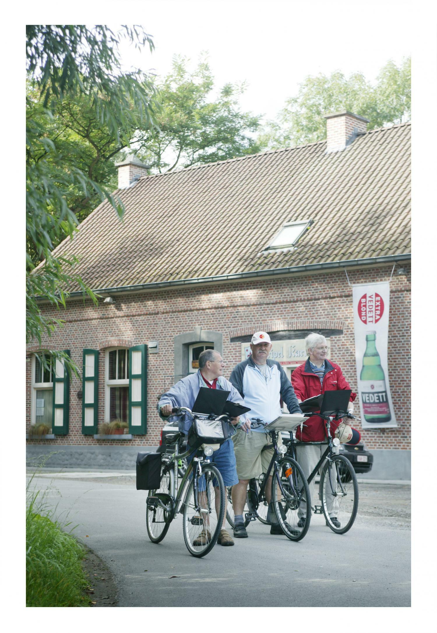 Drie personen wachten met hun fiets aan Den Bunt in Hamme